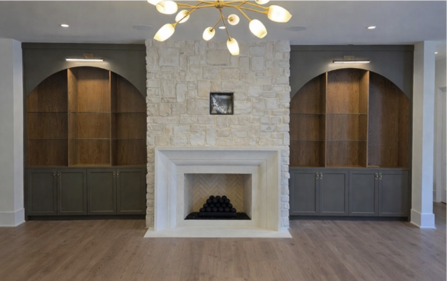 Great room stone fireplace with illuminated arched shelving and built-in cabinets on both sides