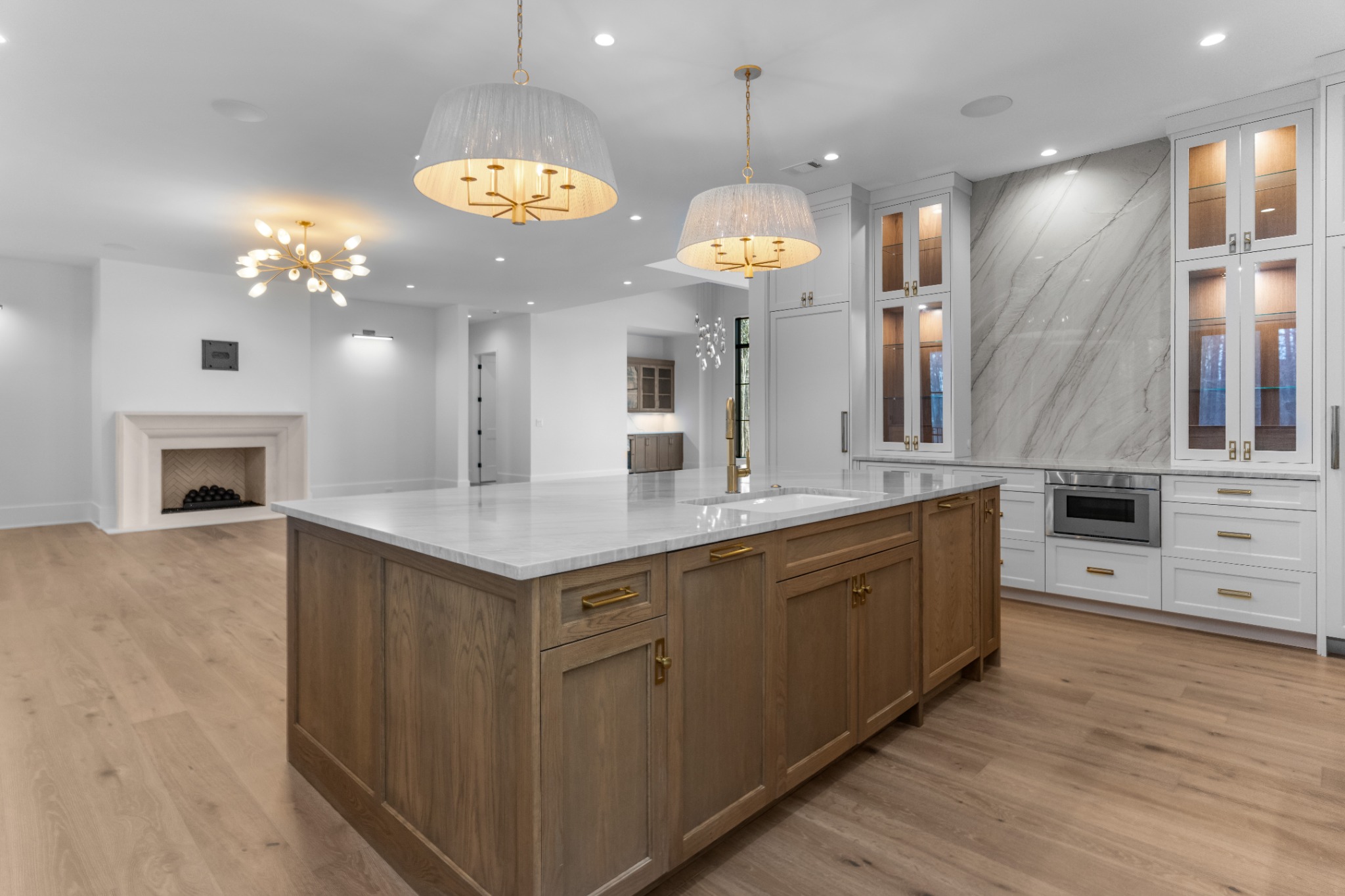 Open kitchen with a large wood island, pendant lights, white cabinetry and stone backsplash