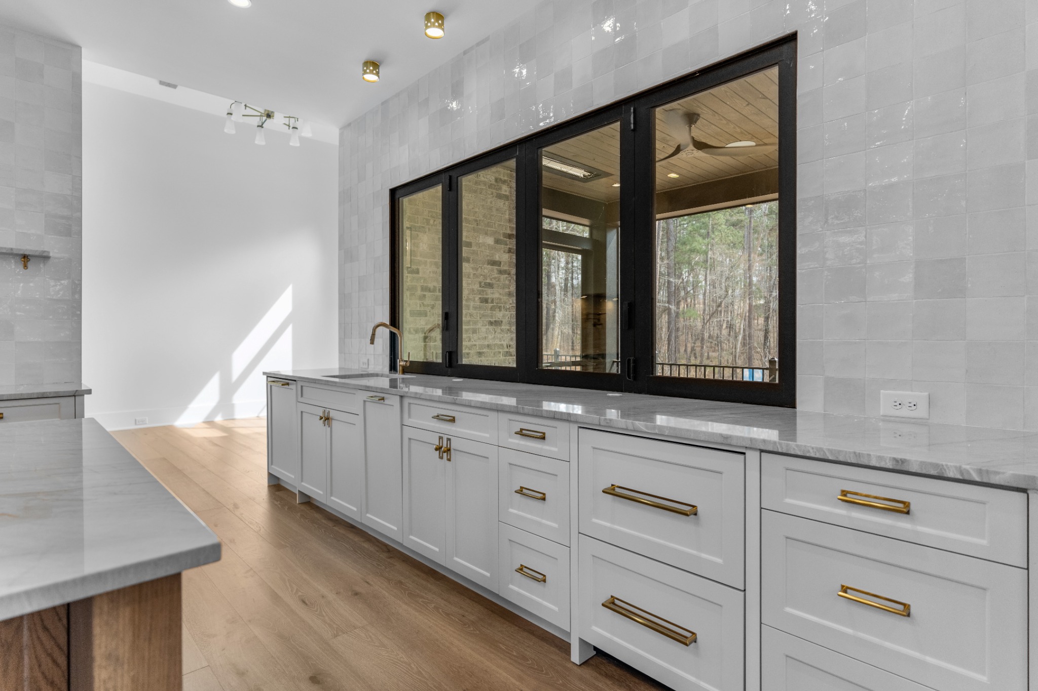 Kitchen counter with white cabinetry and a black-framed pass-through to the covered outdoor space