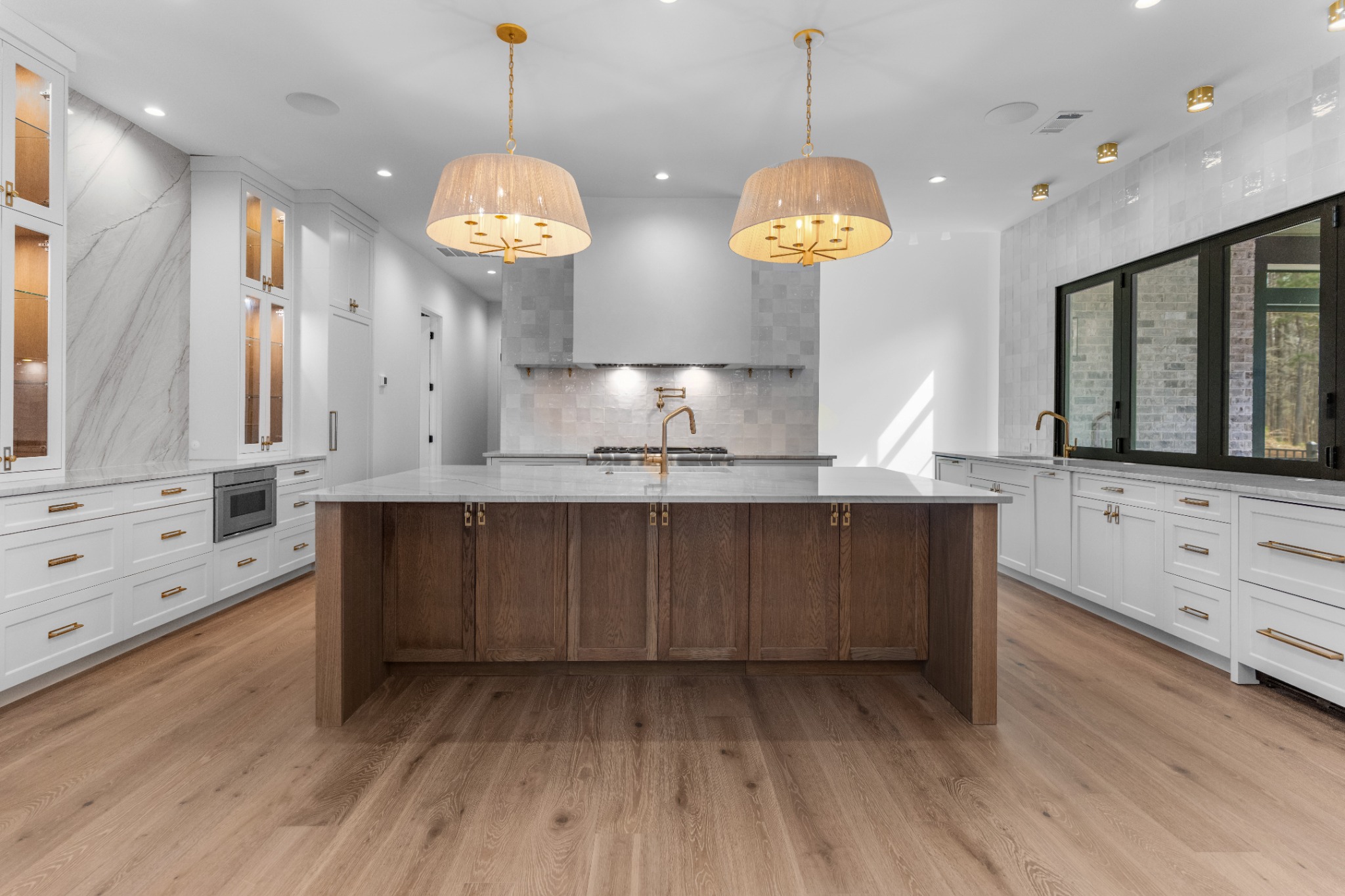 Wide view of the kitchen with a wood island, pendant lights and white cabinetry