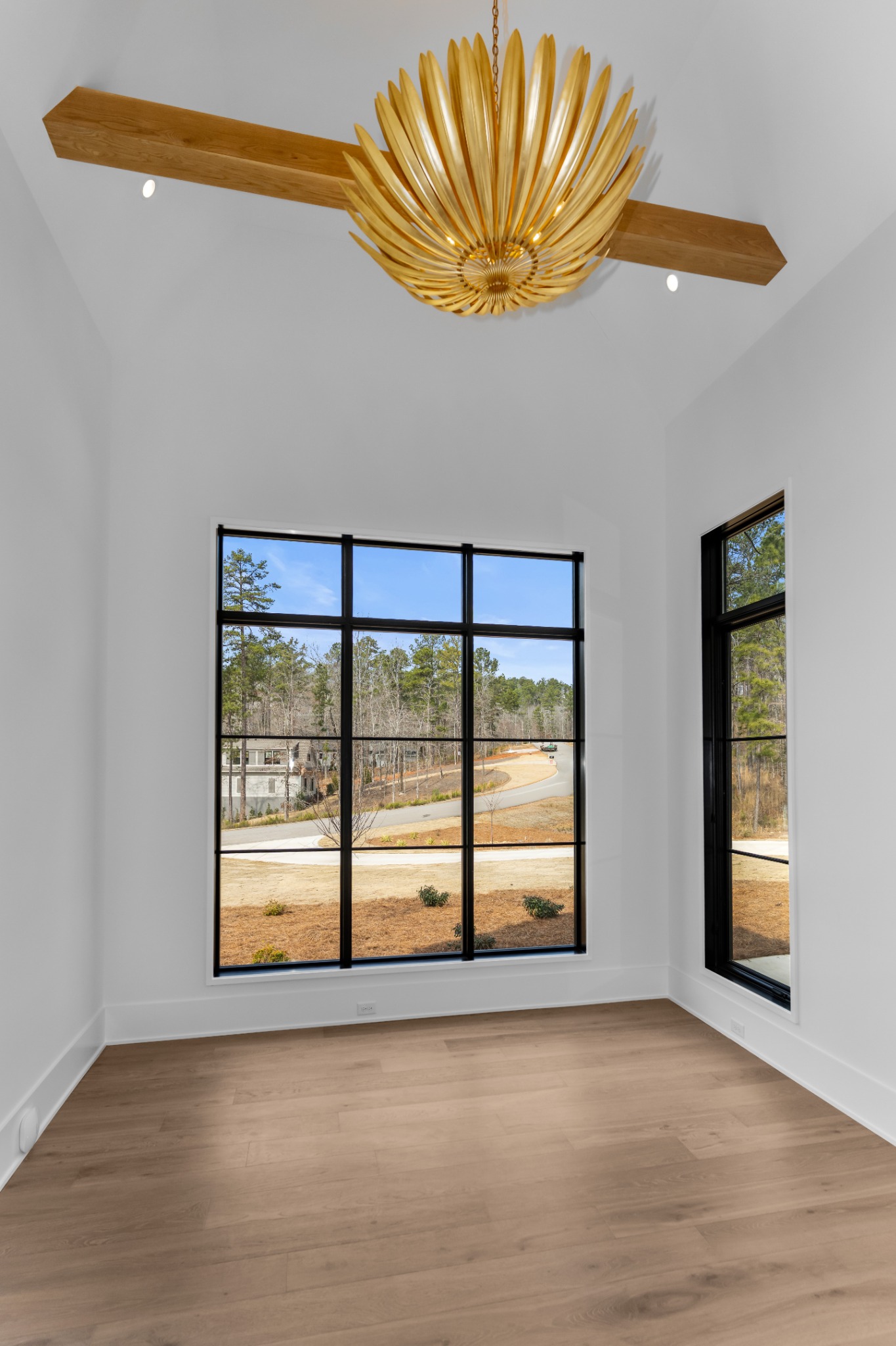 Vaulted office with exposed wood beams and a sculptural ceiling light